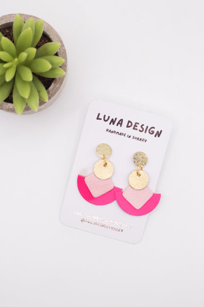 Pink and gold earrings on a Luna Design card with a succulent plant in the background.