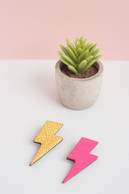 Two colorful lightning bolt-shaped objects on a white surface with a potted plant in the background.