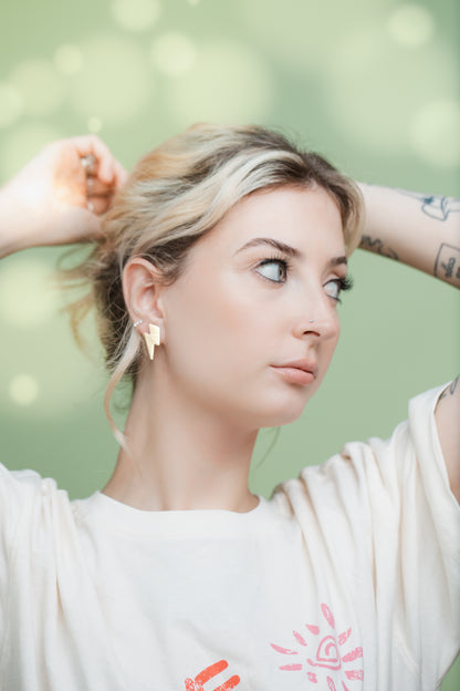 Luna Design model wearing small gold leather lightning bolt stud earrings, handmade with wood backing and hypoallergenic surgical steel posts