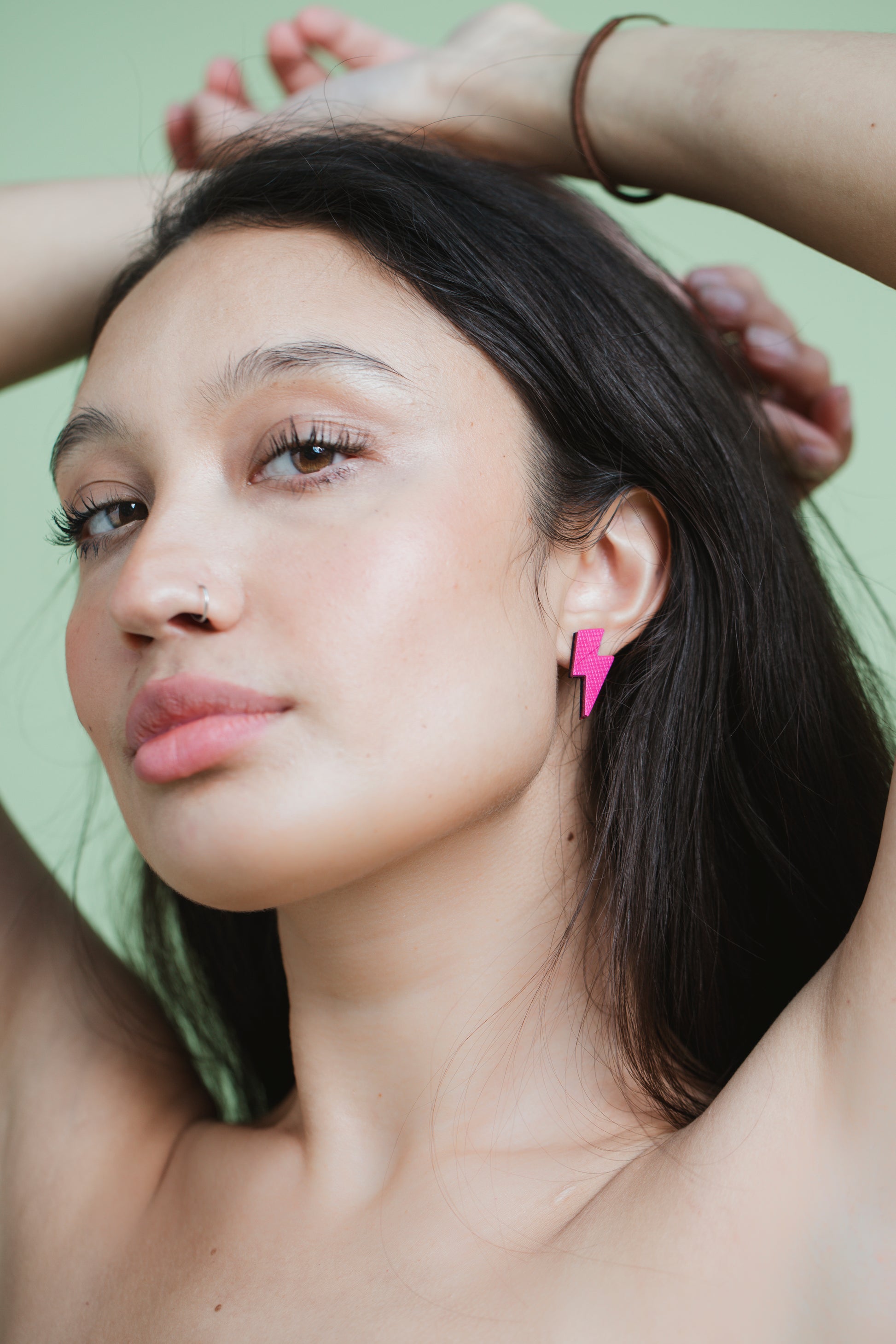 Luna Design model wearing small neon pink leather lightning bolt stud earrings, handmade with wood backing and hypoallergenic surgical steel posts
