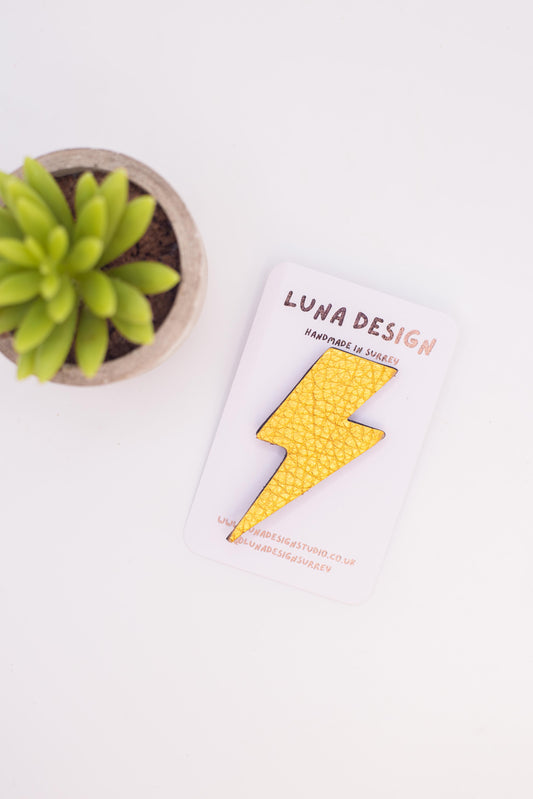 Notebook with yellow lightning bolt design and 'Luna Design' branding next to a small potted plant on a white surface.