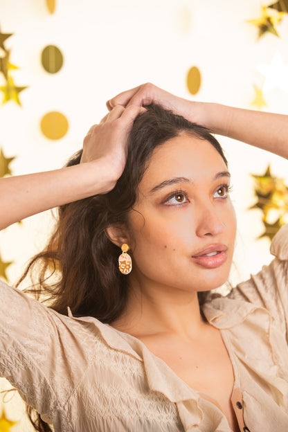Woman with hands in hair against a gold polka dot background