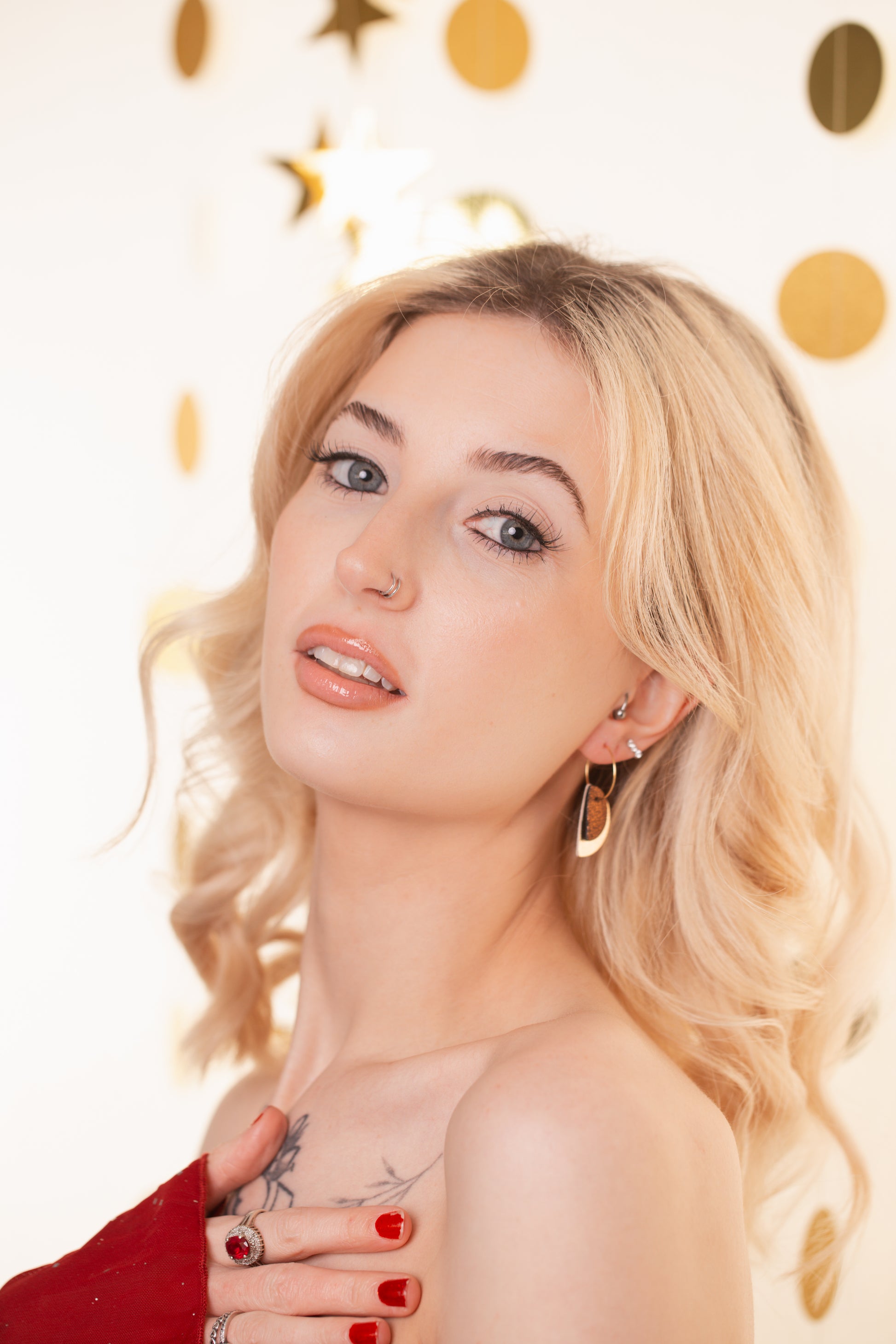Woman with blonde hair and red top against a polka dot background