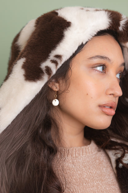 Woman wearing a brown and white patterned hooded jacket against a green background