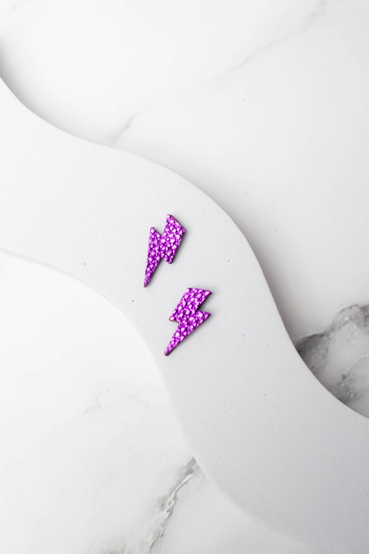 Purple lightning bolt earrings on a marble surface
