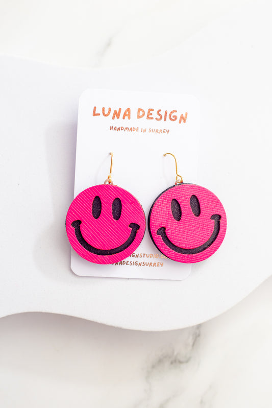 Pink smiley face earrings on a white card with 'LUNA DESIGN' branding.